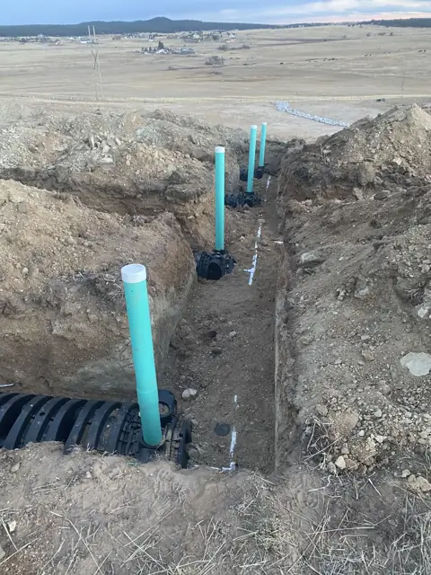 Green pipe risers and drain field chambers in an excavated trench
