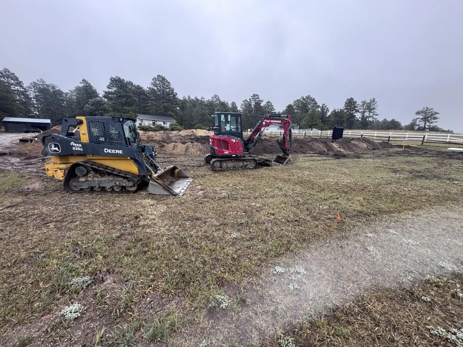 Track loader and compact excavator on a rural job site