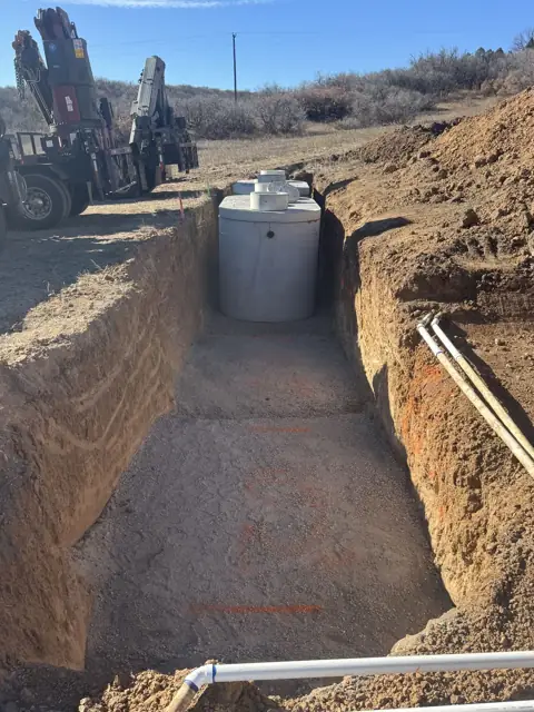Septic tank in an open trench with a crane truck in the background